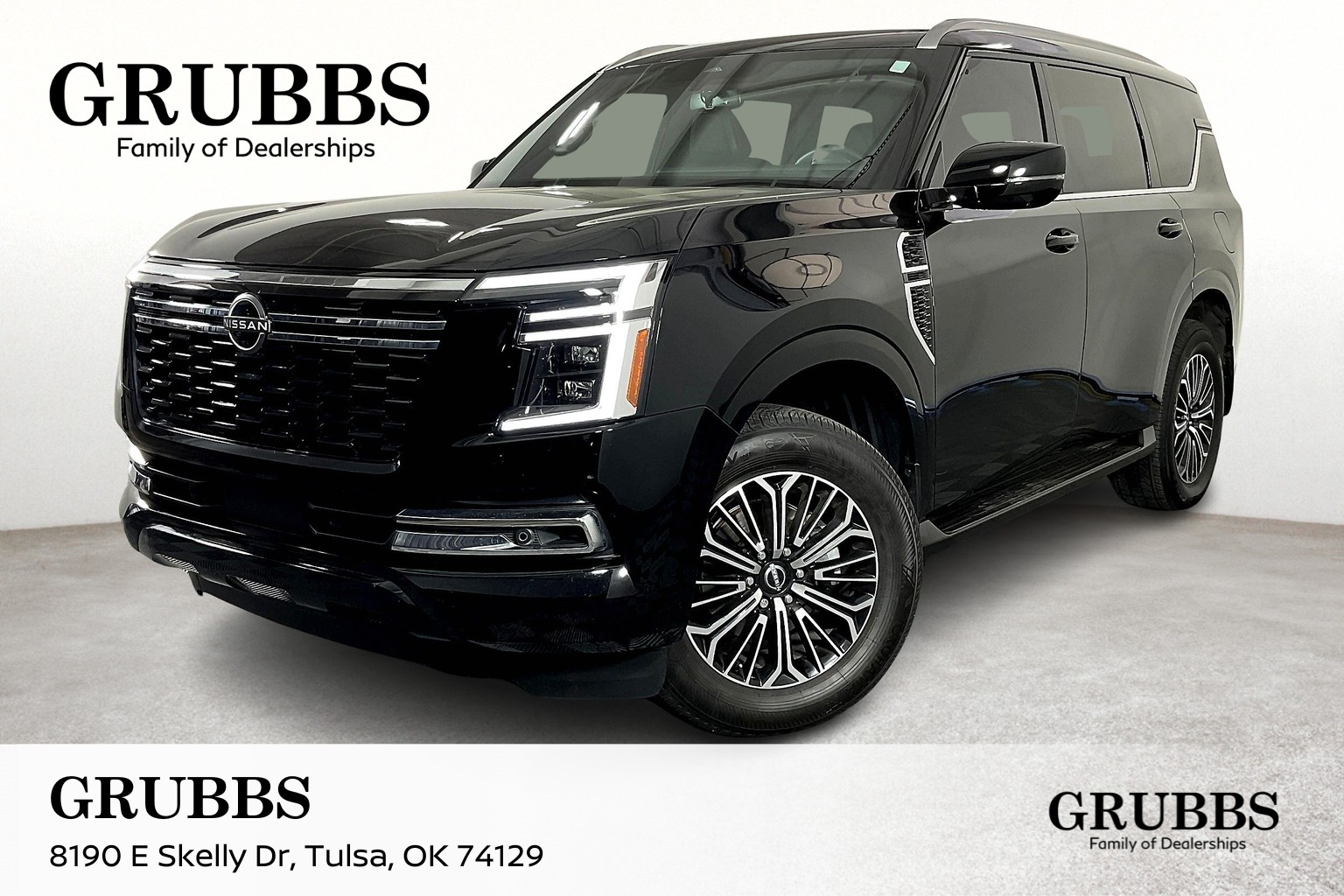 A black 2025 Nissan Armada SUV parked in a showroom, showcasing shiny rims and sleek design.