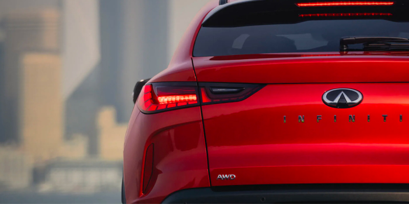 A close-up of the rear of a red 2025 INFINITI QX55 showing the taillights and AWD badge.