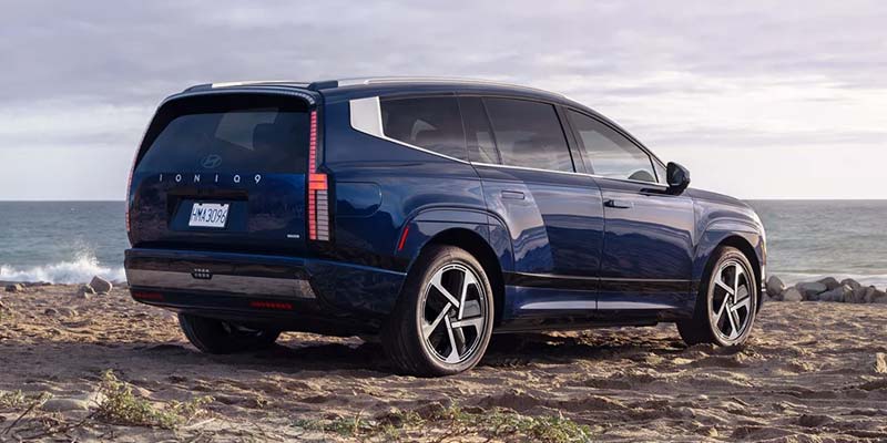 A blue 2026 Hyundai IONIQ 9 SUV parked on a beach near the ocean.