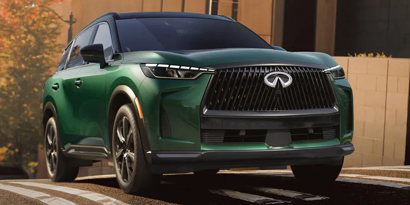 A green 2026 Infiniti QX60 is seen driving on the road in Grapevine, TX, showcasing its front end.