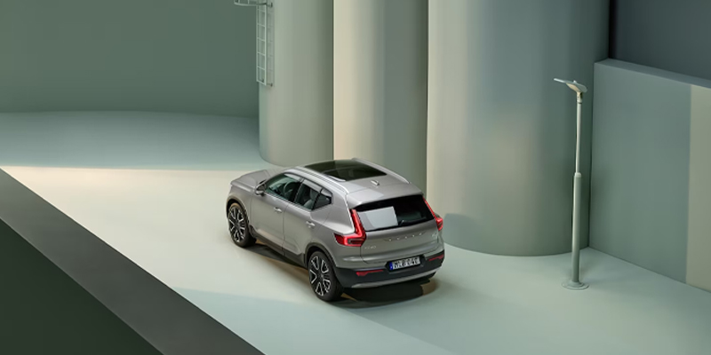 Silver Volvo XC40 parked in an urban setting with large cylindrical structures and a streetlight nearby.